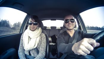 couple with sunglasses driving car merrily