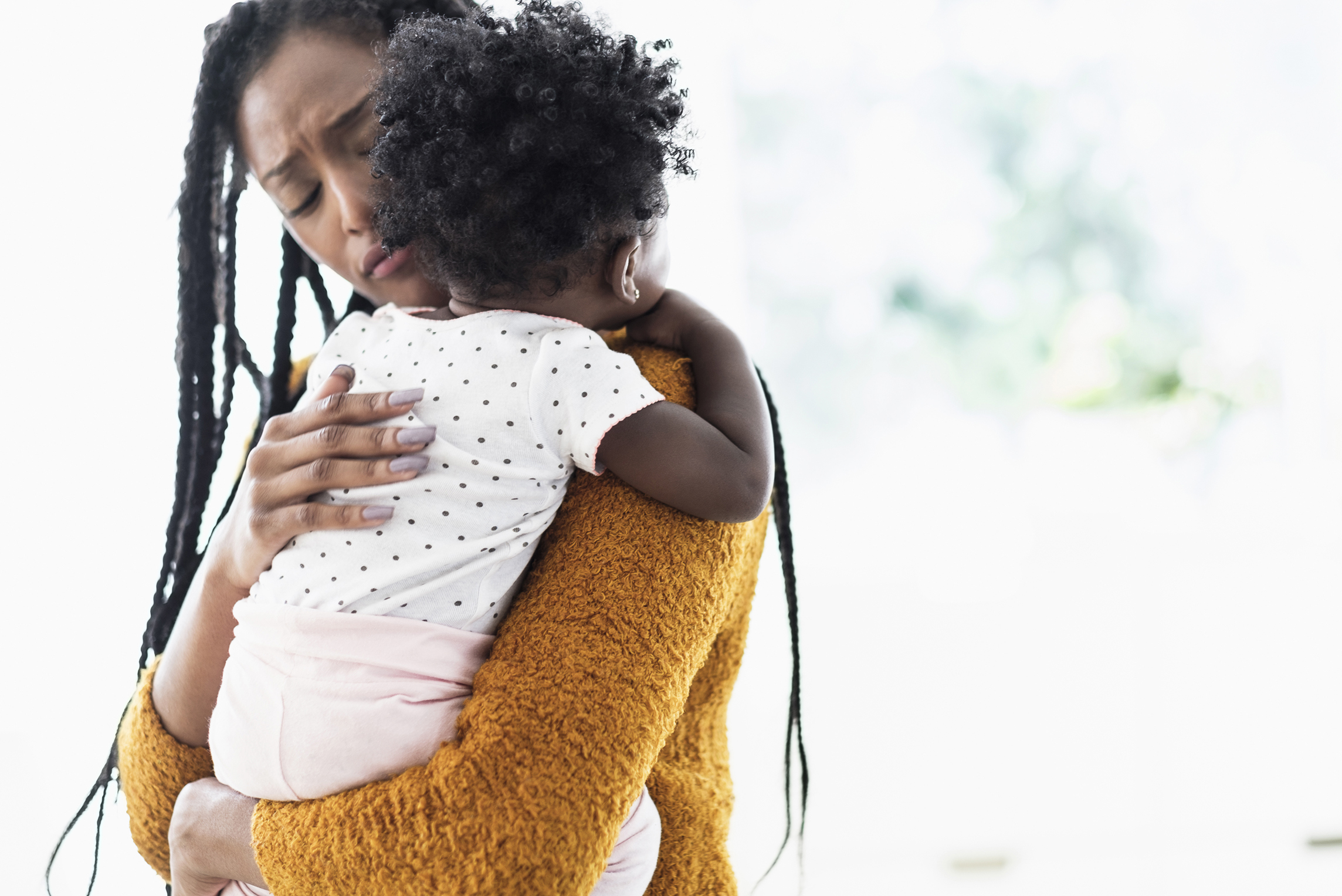 Black woman holding and comforting baby daughter