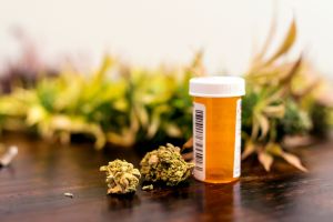 Marijuana buds sitting next to prescription medicine bottle