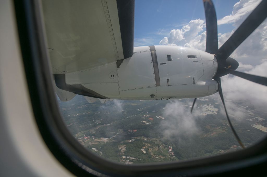 View of Clouds, Land, Sea, Jet Engine and Propeller (with Rolling Shutter) Through Airplane Window