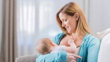 Caucasian mom breastfeeds her baby at home