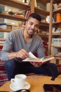 Smiling African American student enjoying book reading in library