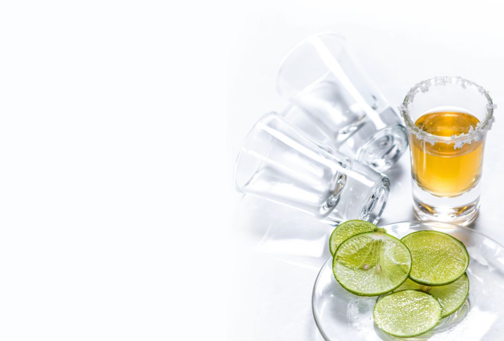 High Angle View Of Tequila Shot By Lime Slices On White Background