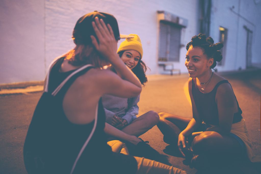 Teen girls sitting on street at night talking and laughing