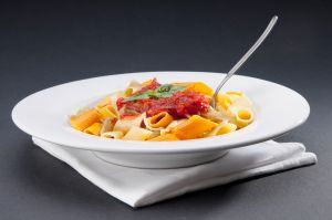 Dish of rigatoni pasta topped with tomato concasse