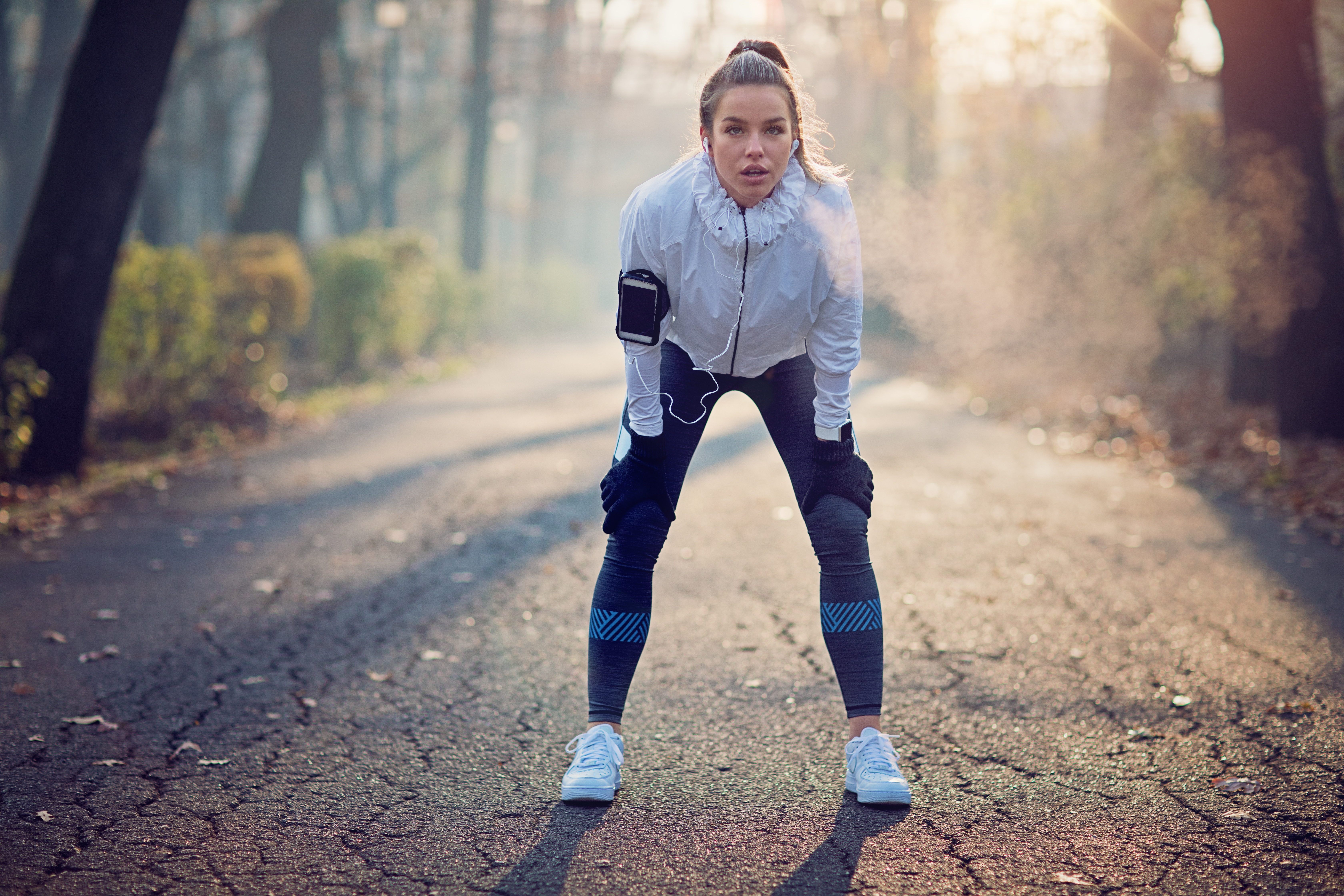 Runner girl is resting exhausted in the foggy morning