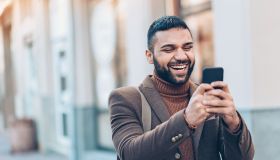 Smiling man with smart phone outdoors in the city