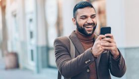 Smiling man with smart phone outdoors in the city