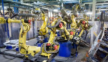 Robots welding body panels on production line in car factory