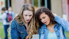 Surprised teenagers look at smart phone