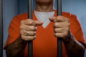 A prisoner standing behind prison bars