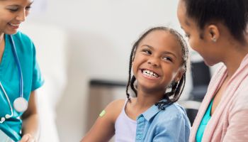 Smiling girl receives immunization from nurse