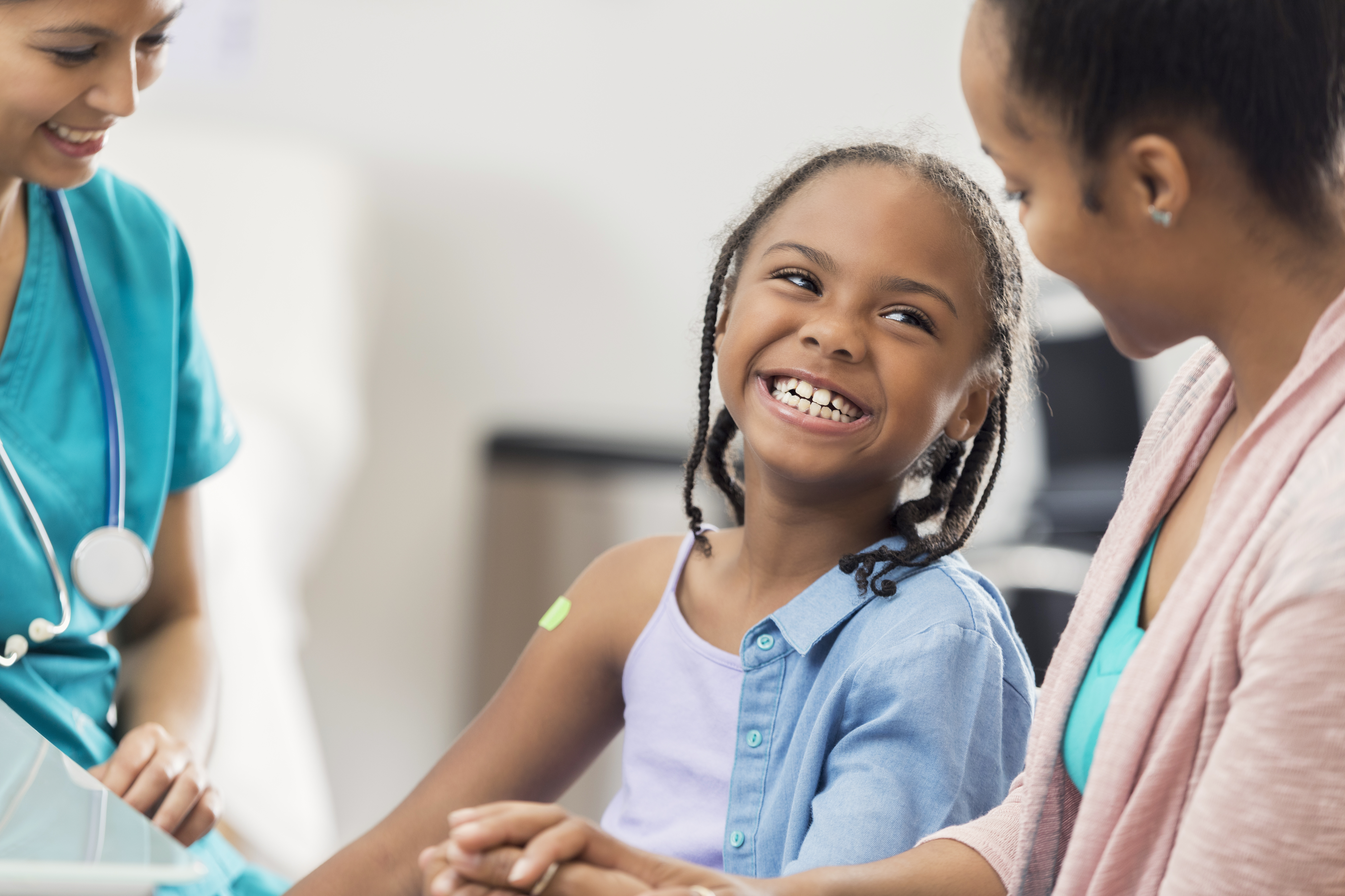 Smiling girl receives immunization from nurse