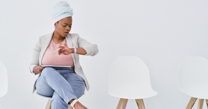 Shot of a young businesswoman checking her watch while waiting for an interview