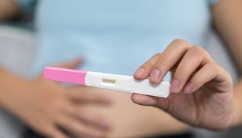A young woman holds a pregnancy test