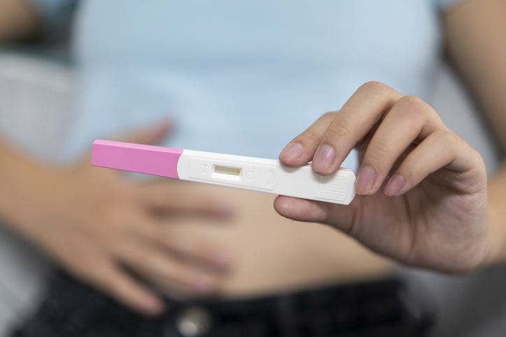 A young woman holds a pregnancy test