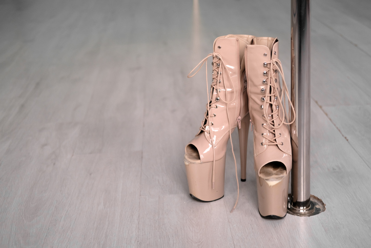 Shoes with high heels stands near the pylon in the dance studio. Shoes for striptease, pole dancing, exotic