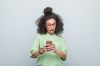 Portrait of surprised young woman using phone