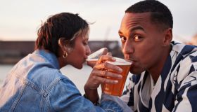Young man drinking beer with girlfriend hand in hand