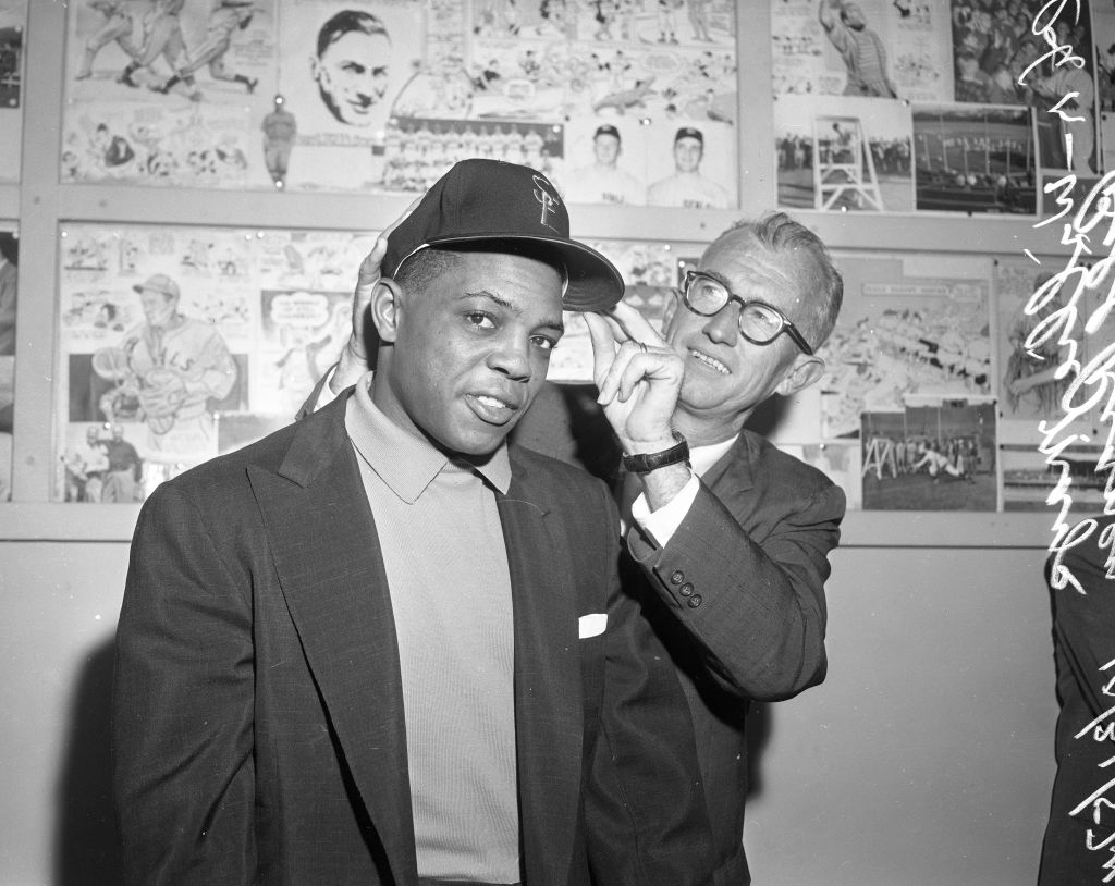Willie Mays tries on a San Francisco Giants cap with the help of manager Bill Rigney, October 31, 1957