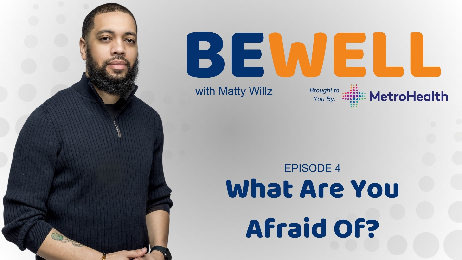 A man with a beard wearing a black sweater stands in front of a "Be Well with Matty Willz" backdrop, brought to you by MetroHealth.